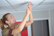 © auremar - happy female worker placing a lamp in the ceiling