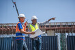 © iPoguz - Diverse engineers discussing blueprints and pointing at construction site project, Professional foreman and engineer supervising industrial logistics and infrastructure building site