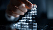 © Sadia - Businessman's hand stacking luminous digital cubes, forming a growth chart, representing data analysis, financial progress, and business strategy.