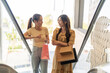 © Art_Photo - Two happy asian women holding paper bags on escalator, Best friends enjoying shopping spree in mall, Consumerism, sale discount, fashion lifestyle, retail business and spending money concept