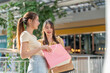 © Art_Photo - Two young asian women friends looking inside pink shopping bag in mall, Excited female shoppers checking new purchased items, Consumerism, summer sale discount, retail therapy and lifestyle concept