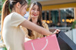 © Art_Photo - Two young asian women friends looking inside pink shopping bag in mall, Excited female shoppers checking new purchased items, Consumerism, summer sale discount, retail therapy and lifestyle concept