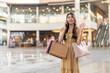 © Art_Photo - Young asian woman holding shopping bags talking on smartphone and waving hand in outdoor mall, Happy female shopper greeting friend on mobile phone, Communication, consumer lifestyle and meeting