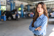 © Art_Photo - Confident asian business woman owner standing with arms crossed in auto repair shop garage, Female manager smiling at car service center, Automotive industry, mechanic and small business concept