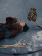 © Stanislav - Top view of woman hunter lying on ice with arrows and eagle owl