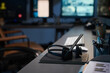 © pressmaster - Empty security office desk featuring wireless headset resting on notebook, computer keyboard and monitor in background, pen holder with pens and documents visible, modern workspace setting