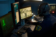 © pressmaster - Black man wearing headset monitoring multiple computer screens in security control room, focusing on surveillance footage and data analysis during night shift