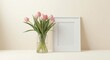 © pngking - Mockup featuring pink tulips arranged in a clear vase beside a white frame on a pale backdrop