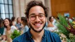 © imagineRbc - A man with glasses is smiling and posing for a picture. He is surrounded by a group of people, some of whom are also smiling. Scene is happy and friendly