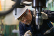 © Supachai - Professional technician checking industrial drill machine precision manufacturing factory. Metalworking engineer wearing safety helmet glasses operating heavy equipment mechanical maintenance workshop