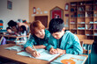 © Marko Geber - Two boys studying and writing together in classroom