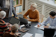 © Seventyfour - Group of middle aged and senior Caucasian women and men participating in educational meeting, sitting at table with laptops and notebooks, listening and taking notes during discussion
