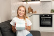 © brizmaker - Woman smiling and holding a wrapped gift box in hands