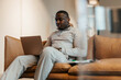 © Maskot - Young male entrepreneur working on laptop while sitting on sofa at office