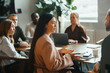 © Maskot - Side view of businesswoman explaining strategies to colleague sitting in meeting room