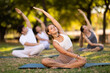 © JackF - People group in park practicing yoga outdoor. Active pastime together, performing gymnastic exercise. Yoga lesson visitors and girl coach do padmasana. People practice sports during yoga in nature
