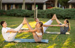 © JackF - Yoga practice in park at sunset. Guy and girl practice pair yoga during group session, perform Buddy boat asana