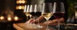 © neirfy - Row of wine glasses (white/red) on wooden bar, foreground in focus with bubbles, dark grapes on slate, blurred warm lights, hand partially behind.