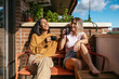 © Alberto - Lesbian couple laughing enjoying morning coffee on balcony