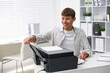 © New Africa - Smiling man working with printer at white desk in office