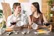 © New Africa - Romantic date. Couple painting on cups at wooden table in studio