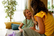 © djile - Mother comforting daughter while talking at home on sofa