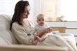 © New Africa - Smiling mother with her cute baby on sofa at home