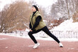 © New Africa - Woman stretching before run in winter park