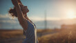 © CStock - A woman enjoying nature with hands raised toward the sky in a serene outdoor setting at sunset.