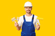 © Pixel-Shot - Portrait of male painter with paint roller and brushes on yellow background