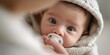 © NovaVision - Close-up portrait of a newborn baby with a pacifier, looking directly at the camera