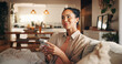 © OnPoint/peopleimages.com - Phone, thinking and typing with woman on sofa in living room of home for break, chilling or me time. App, ideas and text message with happy person in apartment for browsing or mobile communication