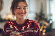 © EricMiguel - Smiling young woman in red knit reindeer sweater holding a mug with both hands, freckled cheeks and messy bun, cozy candlelight and Christmas bokeh