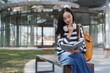 © crizzystudio - Young asian woman student reading book on campus bench