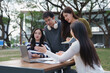 © crizzystudio - Asian college students studying together discussing academic project outdoors