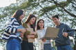 © crizzystudio - Asian students collaborating and discussing academic project outdoors