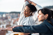 © Westend61 - Women stretching outdoors in sportswear with cityscape in background