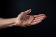 © juliars - Male hand with palm up presenting, supporting, or giving on a dark background