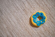 © TrueFrame Collective - Colorful plush toy donut lying on textured carpet, vibrant blue and yellow design with multicolored dots, soft surface suggesting use as pet toy or child plaything, ample copy space