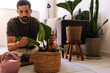 © kleberpicui - Adult man inspecting houseplant leaves indoors, monitoring plant health and practicing mindful home gardening and connection with nature.