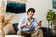 © Bliss - Stylish young man enjoying coffee while checking his phone in a chic modern apartment