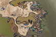 © Amazing Aerial - Aerial view of numerous colorful boats clustered around the sandy banks, creating a vibrant mosaic against the earthy tones of the water, Sylhet, Sylhet Division, Bangladesh.