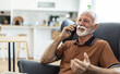 © Jelena Stanojkovic - Shot of an elderly man on a call using his cellphone on the sofa at home. Elderly guy enjoys online chatting, spends time in social networks, using phone and smiles.