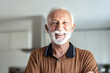 © Jelena Stanojkovic - Portrait of happy retired senior man standing at home near window. Satisfied old man in casual clothes looking at camera and smiling while standing near the window.