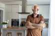 © Jelena Stanojkovic - Portrait of happy retired senior man standing at home near window. Satisfied old man in casual clothes looking at camera and smiling while standing near the window.