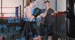 © vectorfusionart - Training female boxer in black sport top, coach guiding punches at boxing gym with data overlay