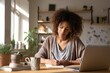 © Olena - Focused Black woman student at a desk using a laptop and taking notes in a bright study space