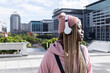 © wavebreak3 - African American female standing on terrace plaza, wearing pink beanie and headphones, copy space