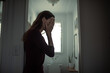 © kieferpix - stressed woman covering face in bathroom doorway, anxiety and depression concept