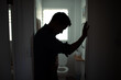 © kieferpix - silhouette of depressed man leaning on bathroom doorway, mental health crisis concept